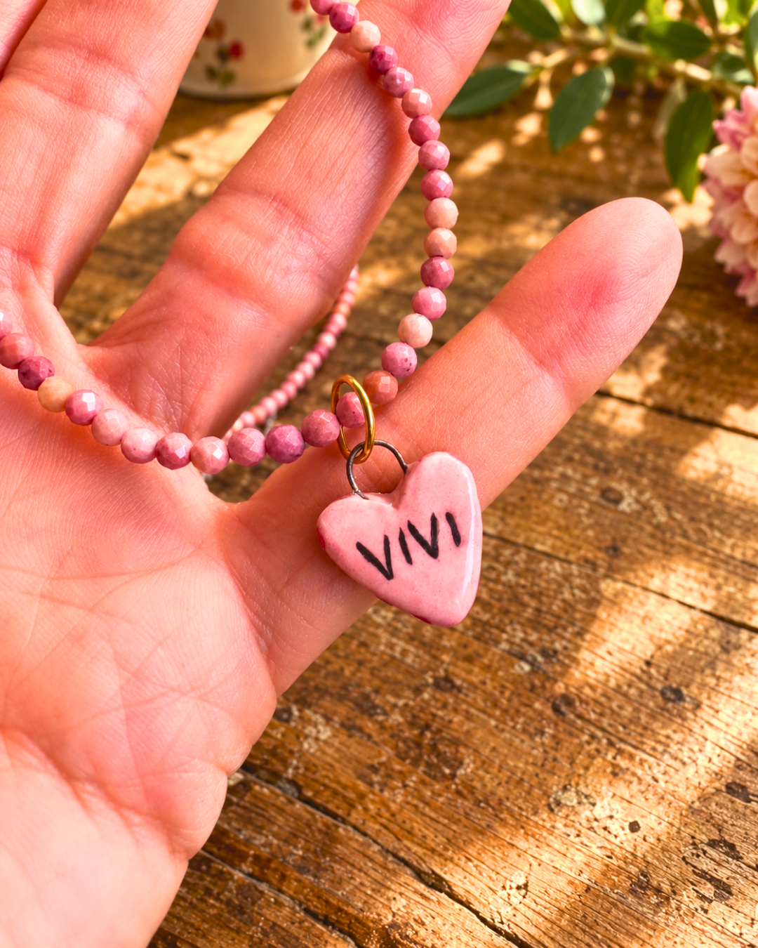 Dettaglio del ciondolo a cuore rosa con scritta VIVI